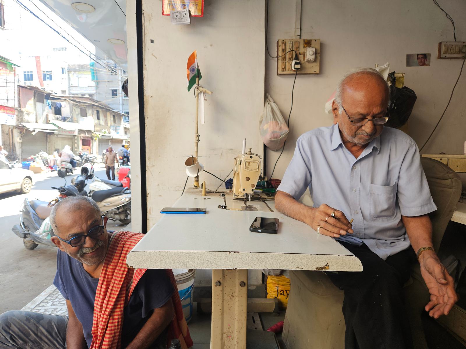 two men in a tailoring shop that opens onto a busy street