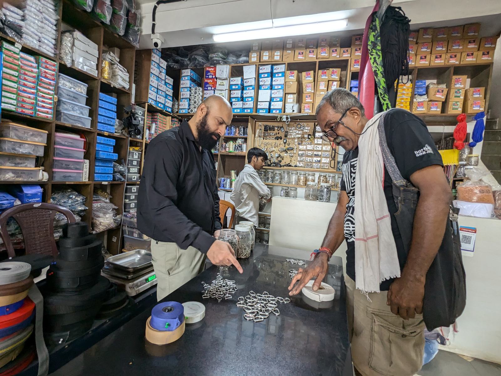 two men pick out metal rings at a trims shop counter