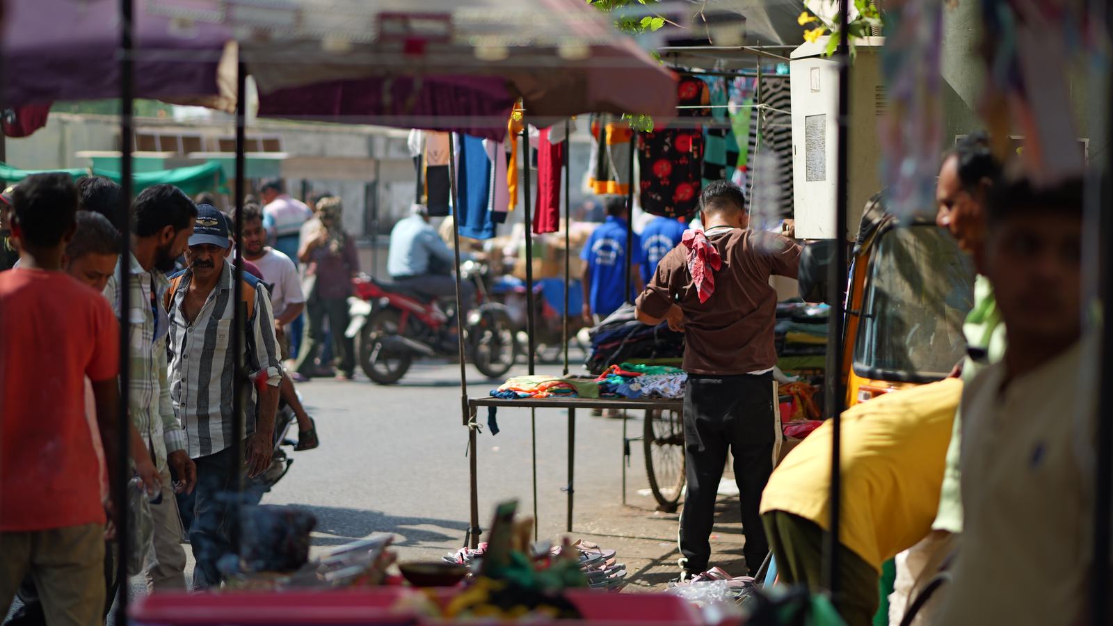 stalls and shoppers at a street market, seen from under a stall awning