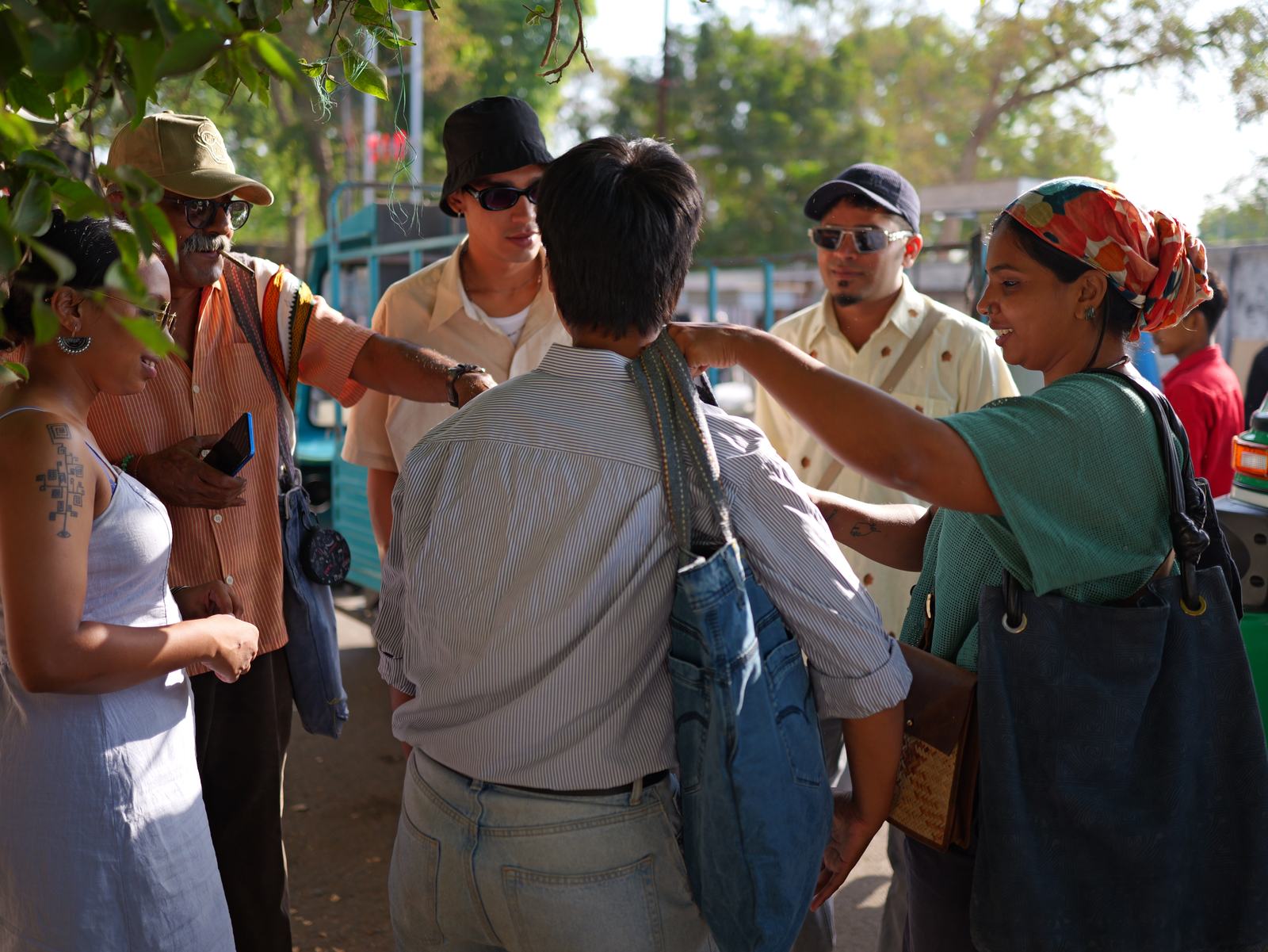 a crowd at the market, several people carrying denim bags