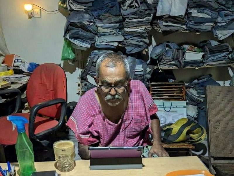 a man at a desk in front of shelves stacked with folded denim