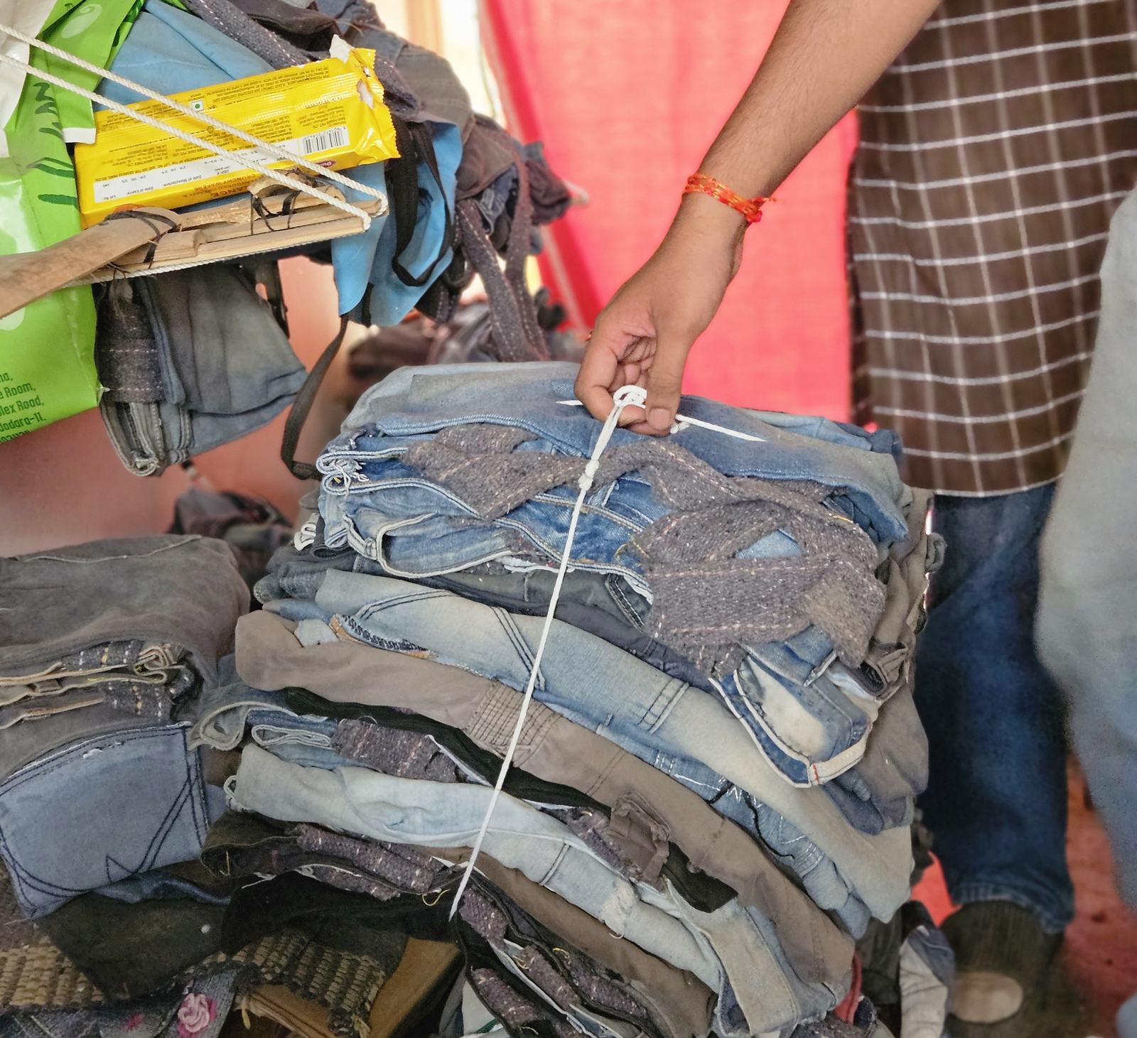 a hand pulls a rope tied around a stack of post-consumer denim in the studio